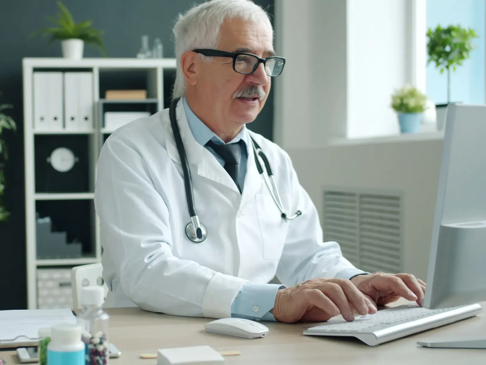 A doctor working at a desk computer in a bright medical office