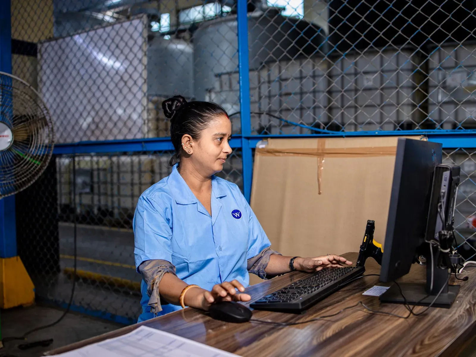 A worker using a computer at a workstation inside a warehouse