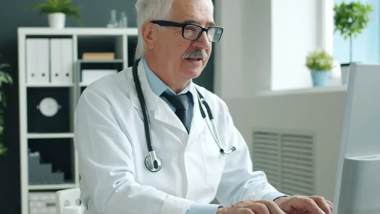 A doctor working at a desk computer in a bright medical office