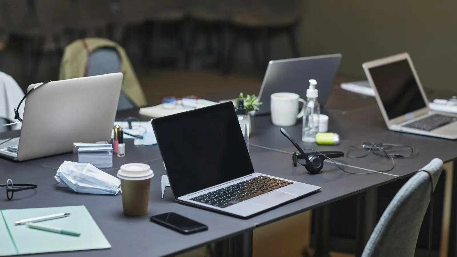 Laptops open on a conference table in an office