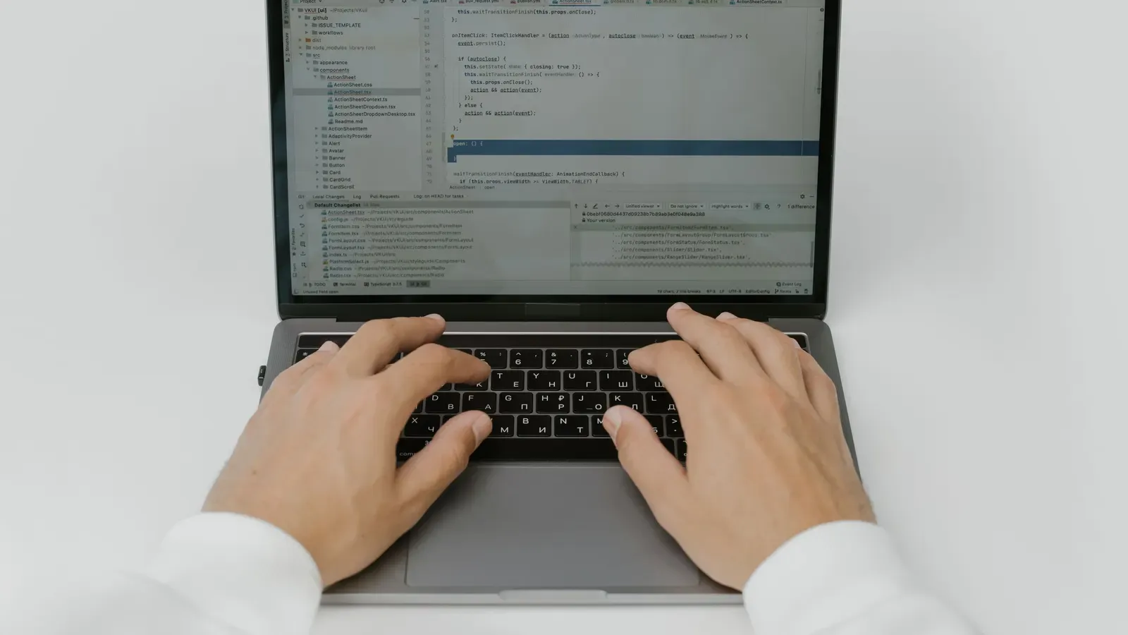 Hands typing on a laptop on a white desk
