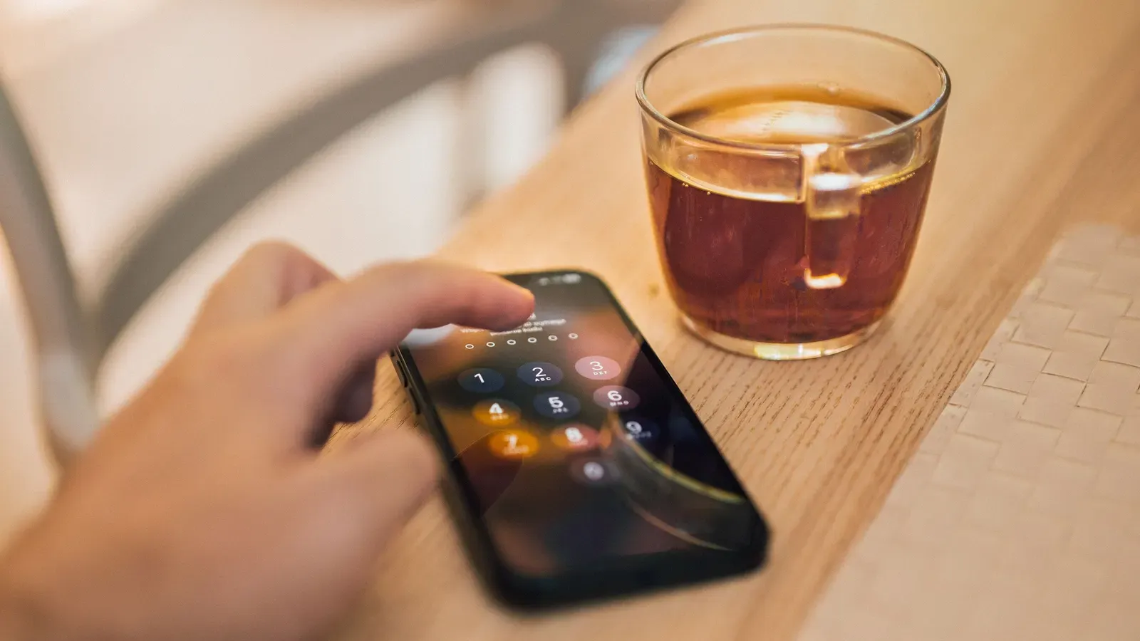 A hand holding a smartphone on a desk