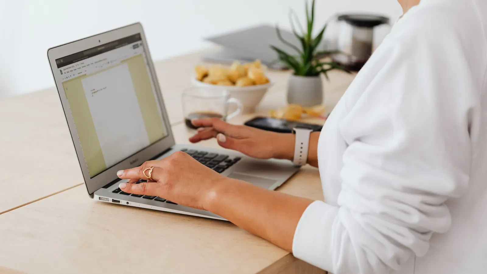Hands typing on a laptop at a home desk